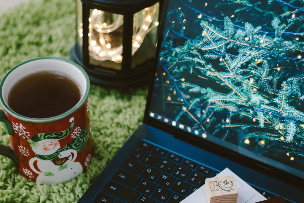 dators ar Ziemassvētku egles zariem, Ziemassvētku krūze ar tēju un lukturis ar lampiņām